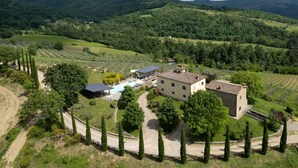 Una villa con piscina, paneles solares y un viñedo al fondo.