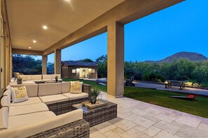 An outdoor patio with a sofa set, a coffee table, and a view of a house and mountains. - 6BR Estate + Guest House, Pool & Spa (Scottsdale)