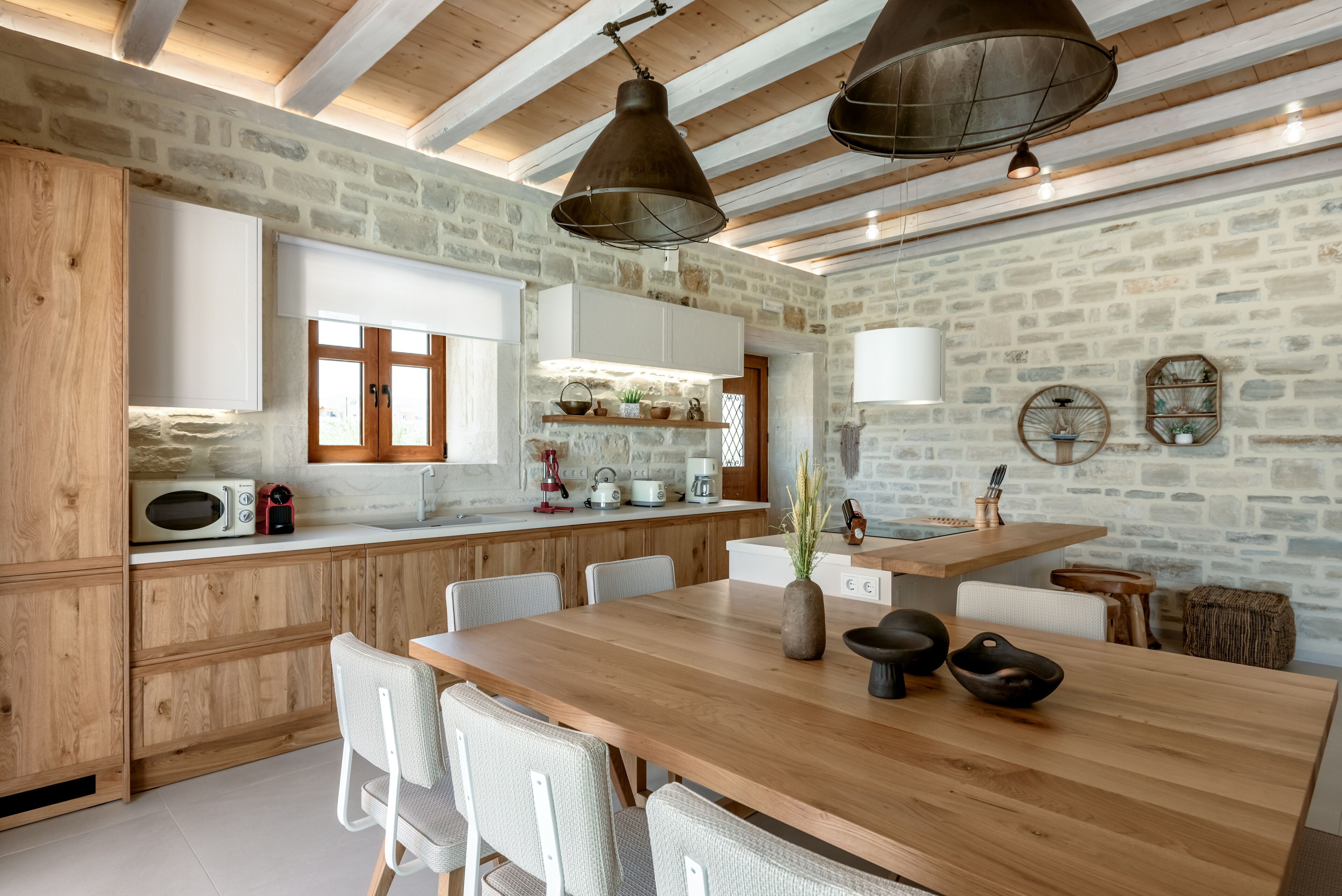 Una cucina rustica con mobili in legno, un muro in pietra e un tavolo da pranzo in legno con sedie.
