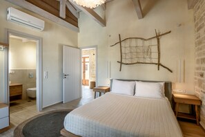 A bedroom with a large bed, wooden headboard, a wall-mounted artwork, and a small bedside table.