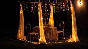 Ein Zelt mit Tisch und Stühlen, verziert mit Lichterketten und Stoffvorhängen.