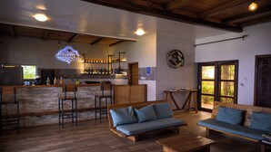 Ein geräumiger Wohnbereich mit Holzboden, eine Bar mit Theke und Hockern sowie eine Sitzecke mit Sofas und einem Couchtisch.