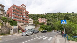 A multi-story residential building with balconies, a pedestrian crossing sign, and a road with parked cars. - Sea view studio Tibor (Budva)