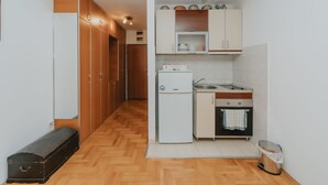 A compact kitchen with wooden cabinets, a white refrigerator, a sink, and a small oven. - Sea view studio Tibor (Budva)