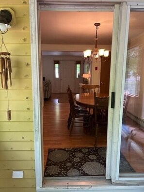 A dining area with a wooden table and chairs, a chandelier, and a patterned rug.