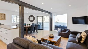 Una sala de estar moderna con un sofá, una mesa de centro y un televisor. Hay un comedor con una mesa y sillas.