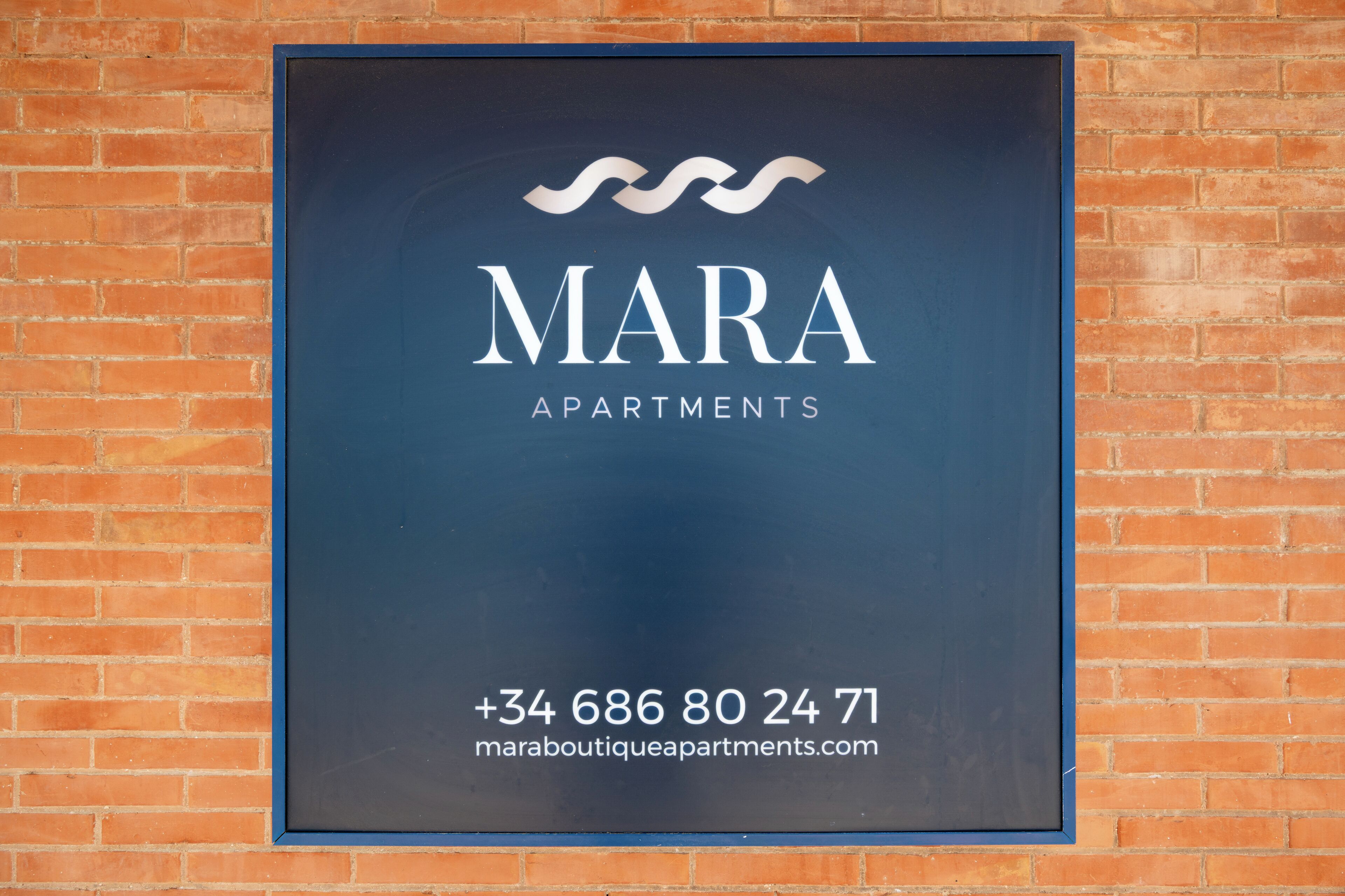 A sign for MARA APARTMENTS with contact information and a website URL.