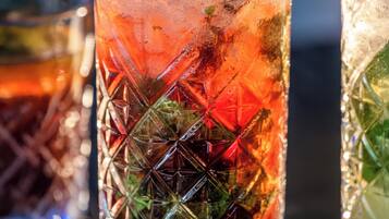 Two tall glasses of iced drinks with mint leaves and a straw, placed on a table.