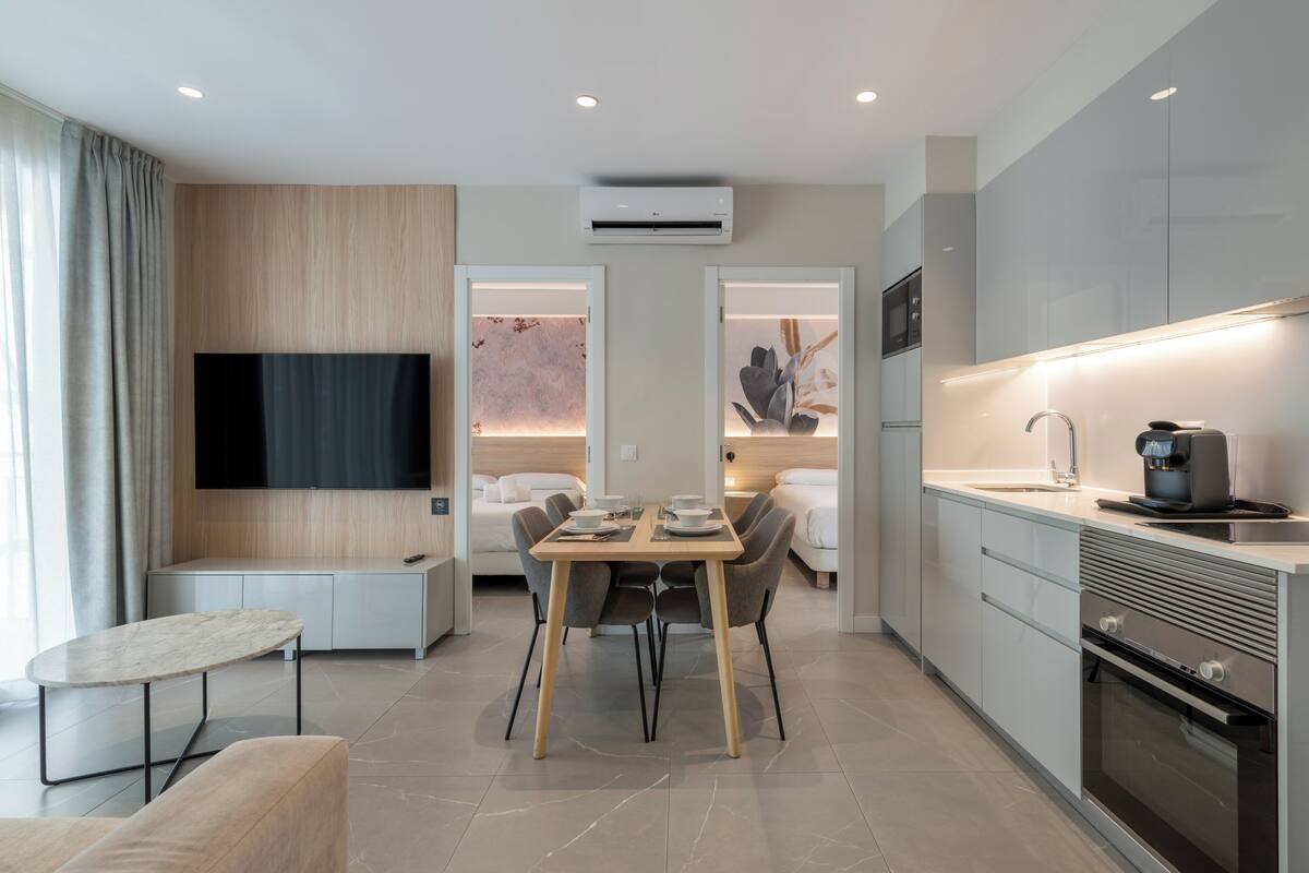 A modern kitchen with a dining area, built-in appliances, and a flat-screen TV.