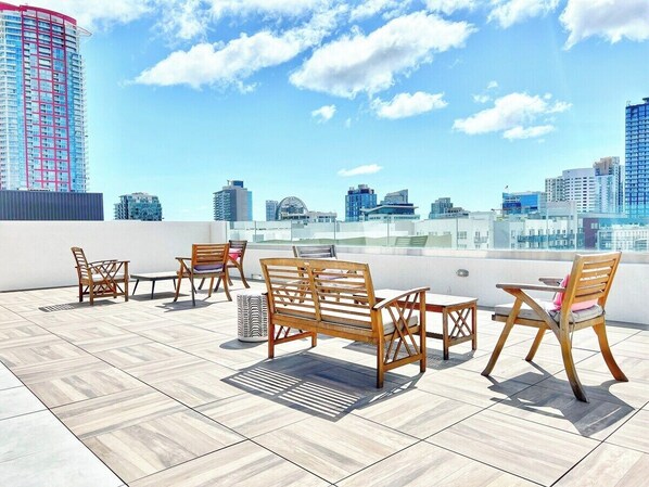Relax on the rooftop with sofas and chairs arranged around a central coffee table, taking in the urban views of the city skyline.