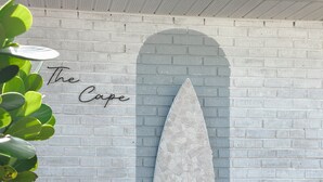 A surfboard mounted on a brick wall with the text "The Cape" above it. - The Cape (Brevard County)