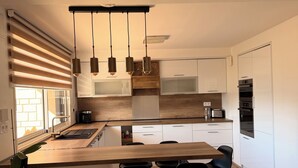 Eine moderne Küche mit einer Holzinsel, Edelstahl-Barhocker und Pendelleuchten.