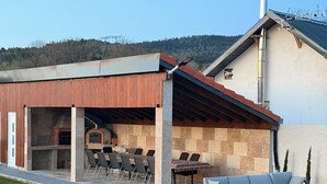 Eine Terrassengruppe im Freien mit Grillplatz, Sitzgelegenheiten und Blick auf die umliegende Landschaft.