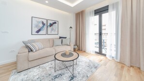 A modern living room with a beige sofa, a round coffee table, and two abstract paintings on the wall. - Salus Hill Condo (Budva)