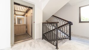 A modern interior with a wooden elevator, a black wrought iron staircase, and marble flooring. - Salus Hill Condo (Budva)