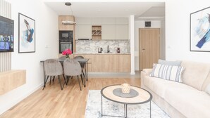 A modern living room with a sofa, coffee table, and dining area. - Salus Hill Condo (Budva)