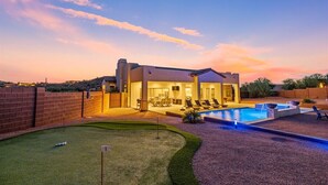 A modern house with a swimming pool, a covered patio, and a well-maintained lawn. - An Arrow Escape! Views, Outdoor Games, Htd Pool & Spa (Gold Canyon)
