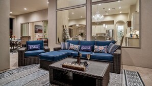 A modern living room with a sectional sofa, a coffee table, and a dining area visible through large windows. - An Arrow Escape! Views, Outdoor Games, Htd Pool & Spa (Gold Canyon)