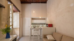 Un espacio habitable compacto con kitchenette, comedor y sofá.
