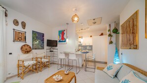 A modern living room with a sofa, chairs, a dining area, and a kitchen. - Casa Flavia by Wonderful Italy (Golfo Aranci)