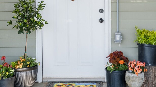A white door with a heart-shaped welcome sign, potted plants, and a light fixture above. - Quiet farm stay, hike, mushroom hunt, see the animals, relax, so much more! (Edmonton)