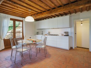 Una cucina con mobili bianchi, un tavolo da pranzo con sedie e un lampadario.