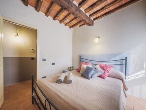 Ein Schlafzimmer mit einem Bett, einem Nachttisch, einer Wandleuchte und einer Tür.