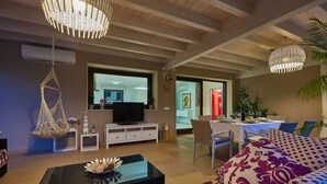 Ein modernes Wohnzimmer mit einer Couch, einem Couchtisch, einem Hängekorbstuhl und einem Essbereich mit Tisch für zwei Personen.