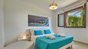 Ein Schlafzimmer mit Bett, Nachttisch, Fenster mit Blick ins Grüne und einem Bild an der Wand.