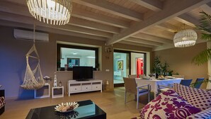 Ein modernes Wohnzimmer mit Fernseher, Sofa und Essbereich.
