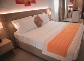 Una habitación de hotel con cama, mesitas de noche, lámpara, espejo y armario.