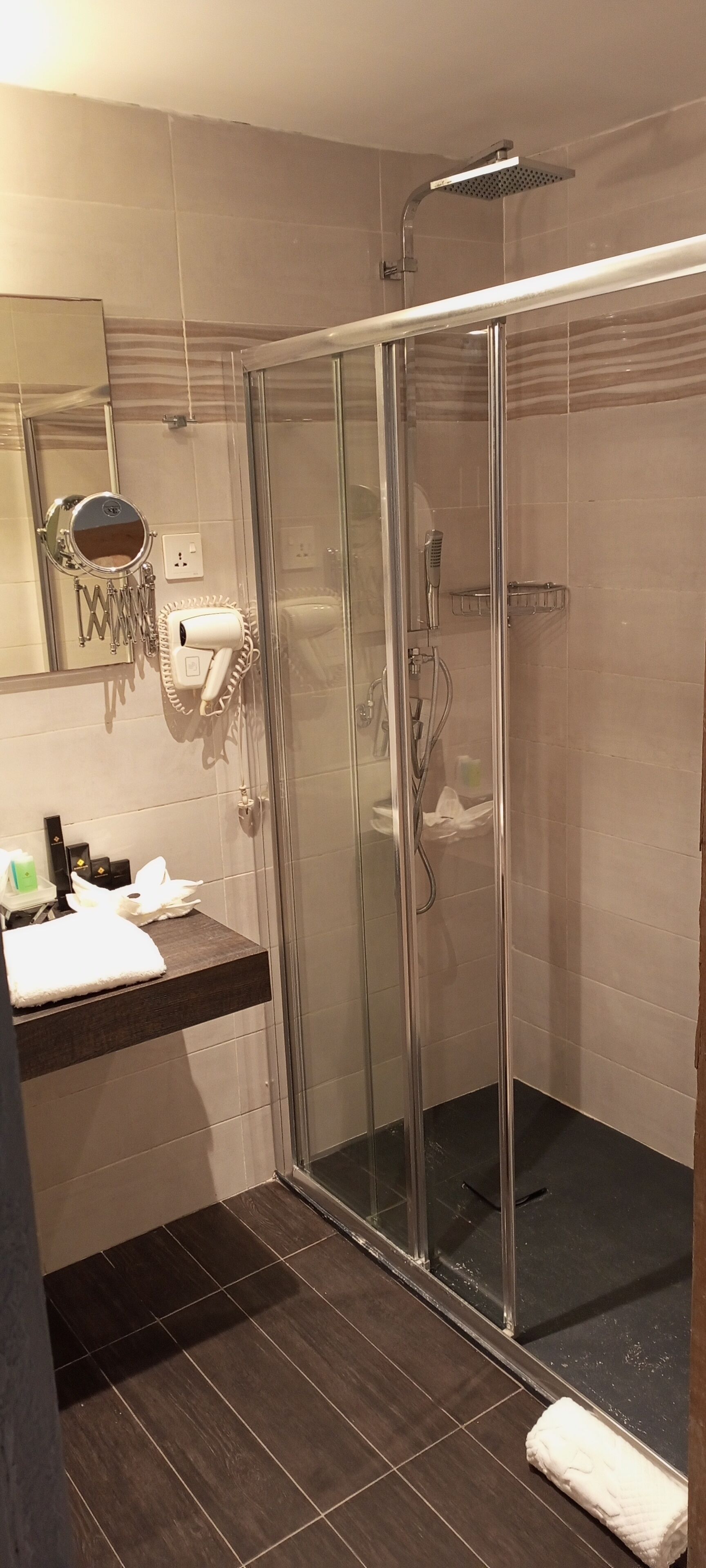 A modern bathroom with a glass-enclosed shower, a vanity with a mirror, and a towel rack.