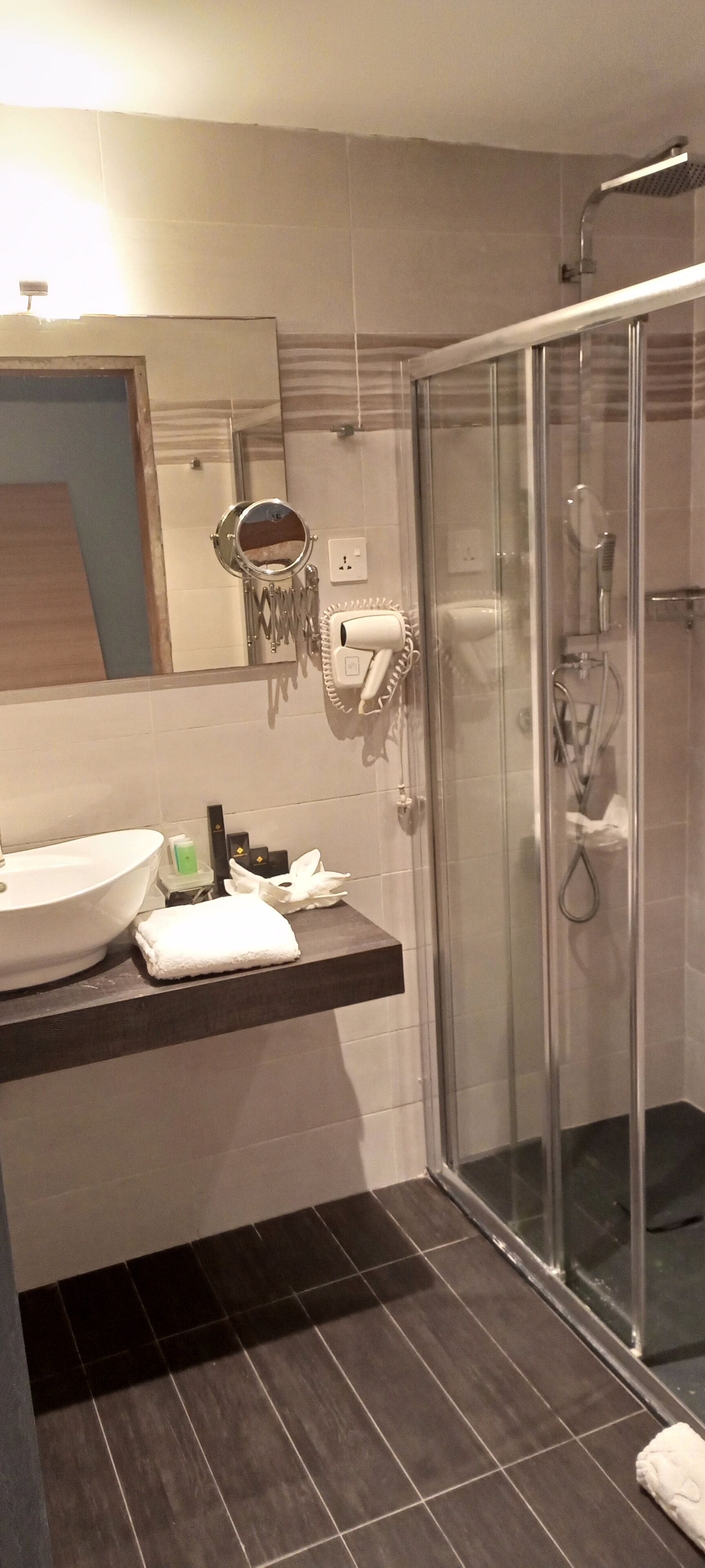 Een badkamer met een groot wit wastafelmeubel, een douchecabine van glas en een handdoekhouder.