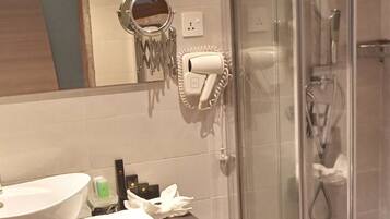 Een badkamer met een groot wit wastafelmeubel, een douchecabine van glas en een handdoekhouder.