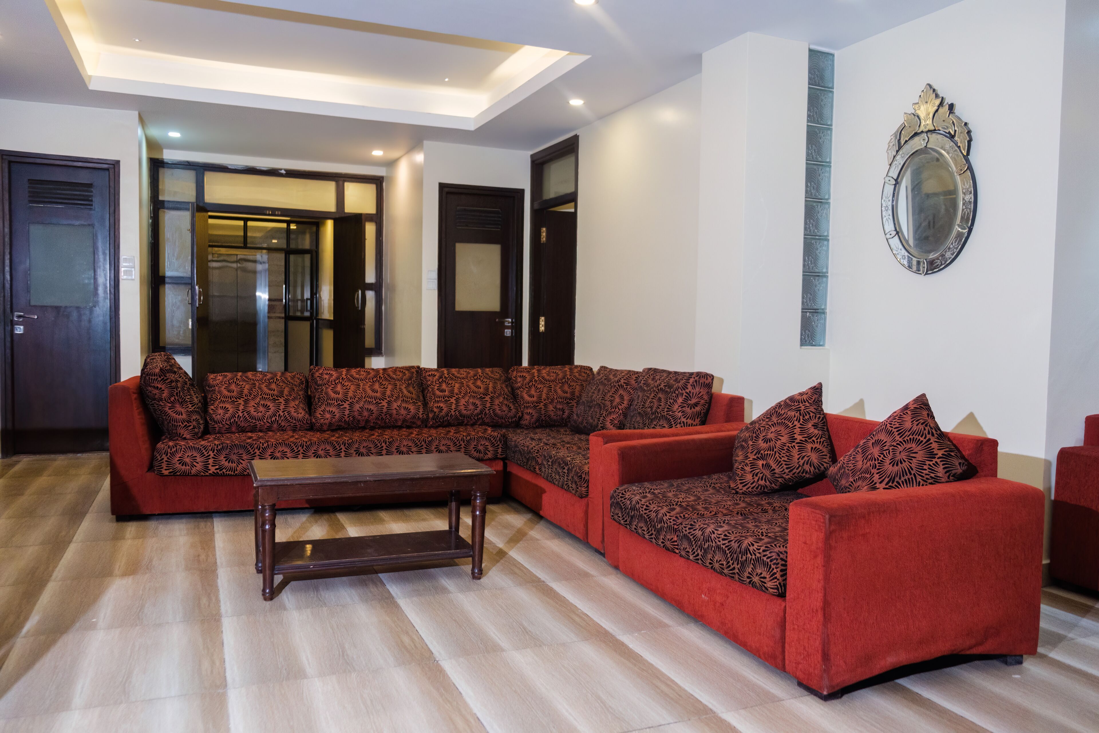 Una sala de estar moderna con un sofá modular, una mesa de centro de madera y un espejo grande en la pared.
