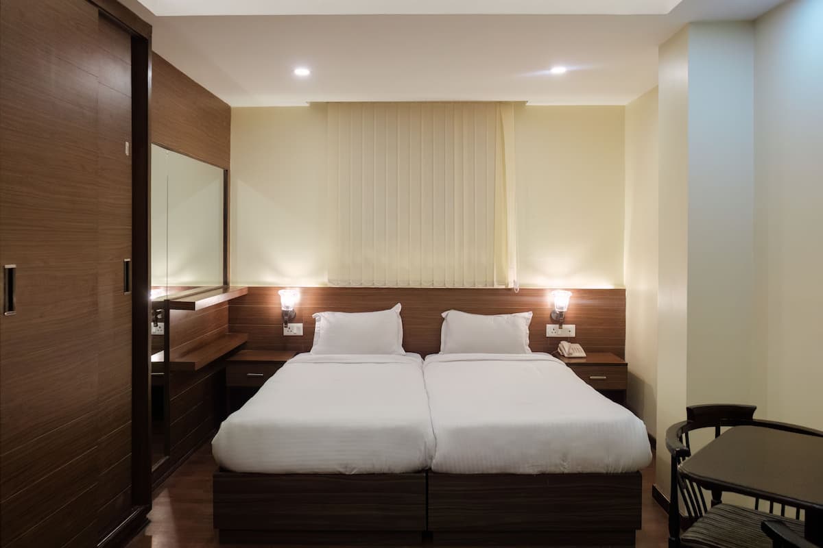 A double bed with two bedside tables, a mirror, and a small table with a chair.