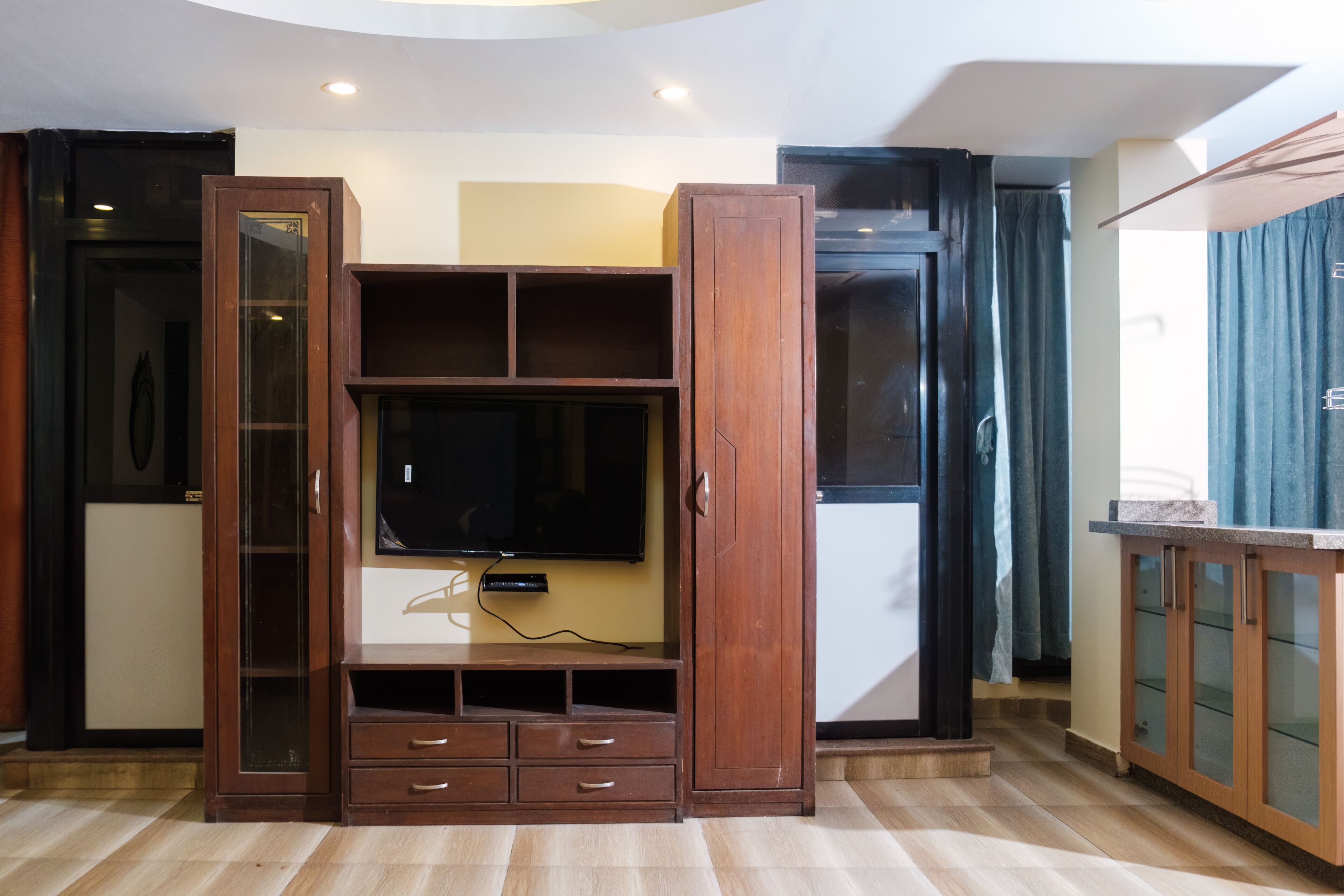 A living room with a wooden entertainment unit, a flat-screen TV, and a built-in cabinet.