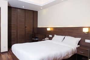 Una habitación de hotel con una cama grande, un armario de madera, lámparas de noche y un escritorio con teléfono.