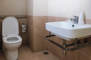 Un baño con inodoro, lavabo y secamanos.