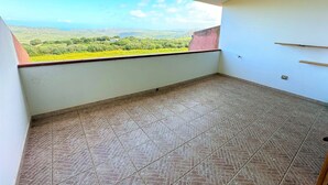 Un balcone con pavimento piastrellato e vista su un paesaggio verde.