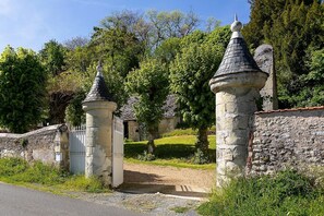 Een stenen poort met twee torens, een stenen muur en een gebouw op de achtergrond.
