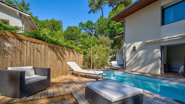 Une terrasse en bois avec une piscine, des meubles en osier et une clôture en bambou.