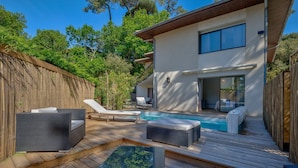 Un espace piscine extérieur moderne, doté de chaises longues et d’une terrasse en bois.