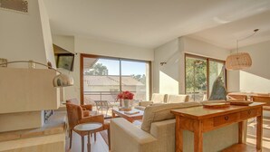 Un salon spacieux avec une grande fenêtre, une table basse en bois et un canapé.