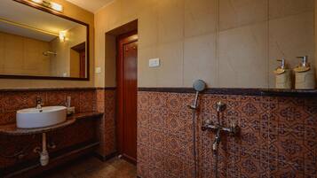 A bathroom with a sink, mirror, shower, and patterned tiles.
