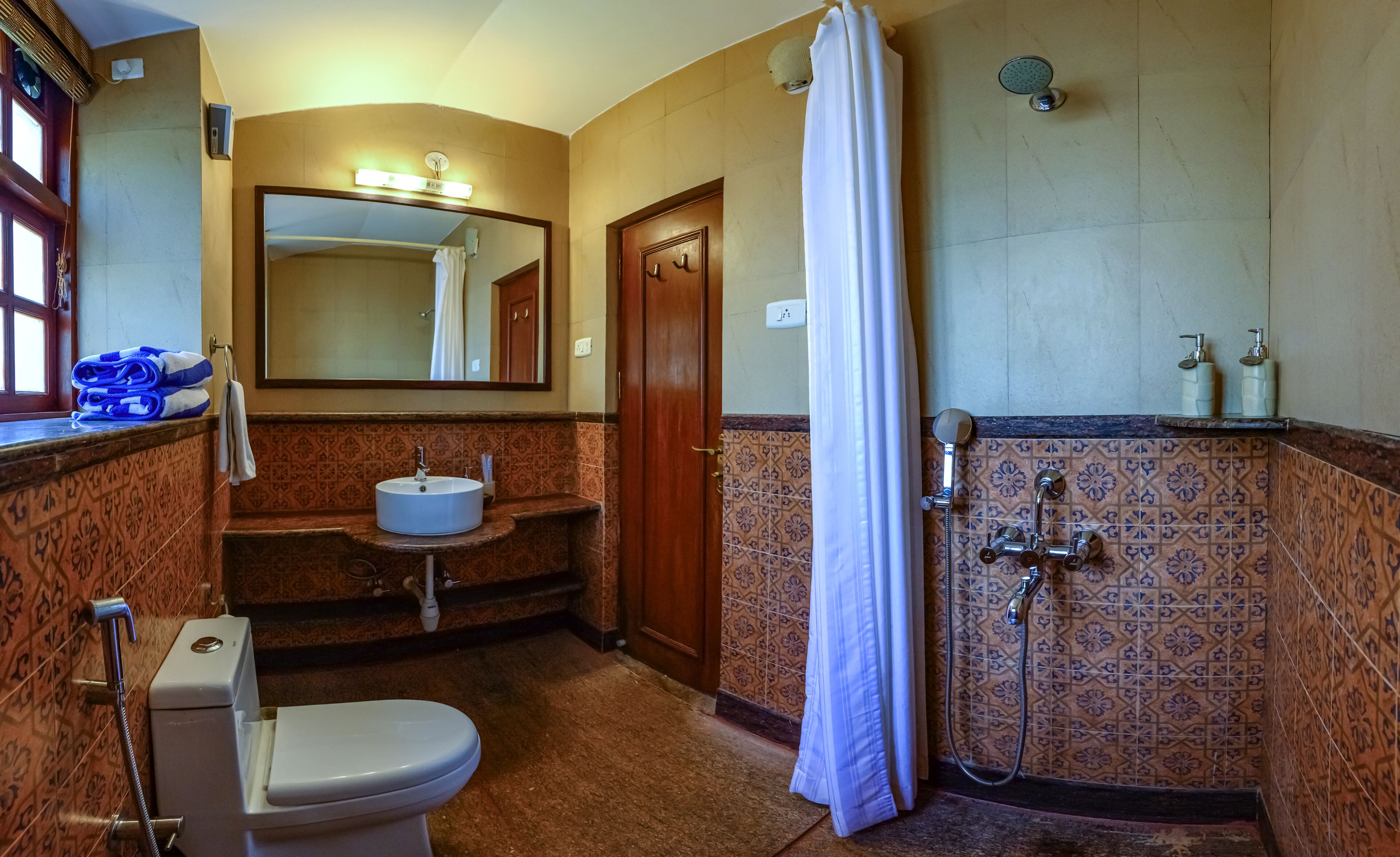 A bathroom with a toilet, sink, shower, and a mirror.