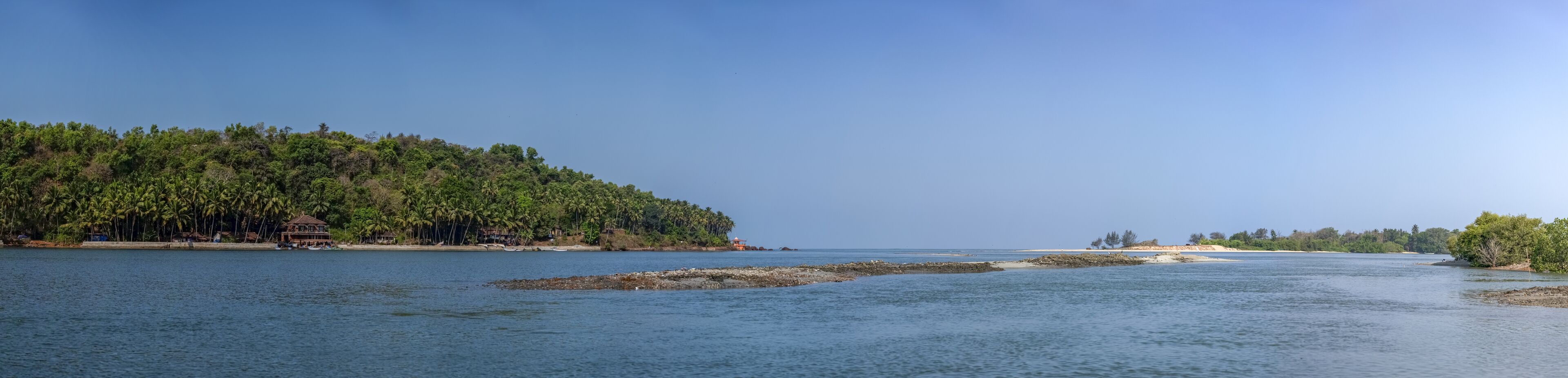 Un paysage côtier avec une plage, une maison et un phare.