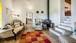 A cozy living room with a checkered rug, two armchairs, a sofa, a fireplace, and a staircase. - Rustic 3-bedroom Country Retreat With Pool, Free Wi-fi, and Breathtaking Views (Tavira)