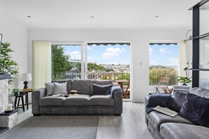 Relax in this stylish living room with a sofa, armchair, and large windows offering a view of the surrounding area.