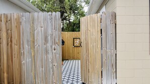 Une porte en bois mène à une pièce dont le sol est décoré de motifs géométriques.